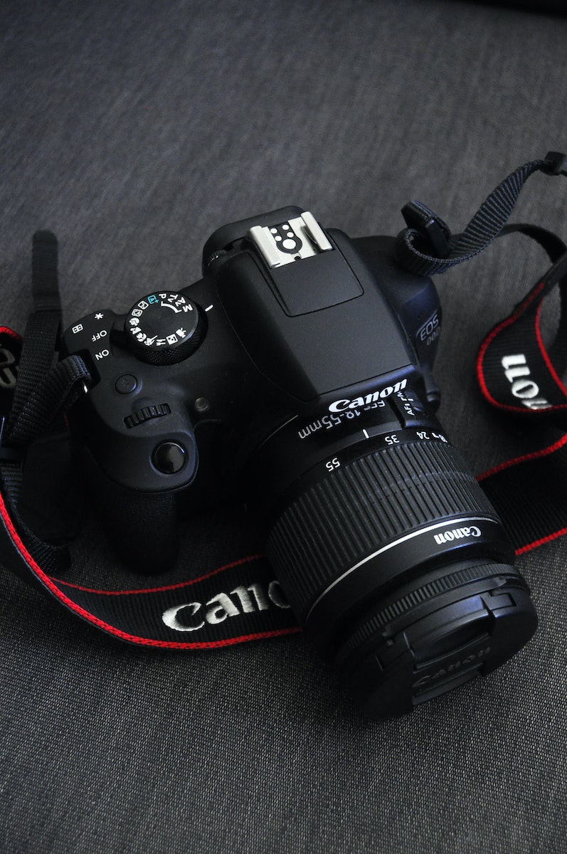 From above of modern black photo camera with professional lens placed on gray surface
